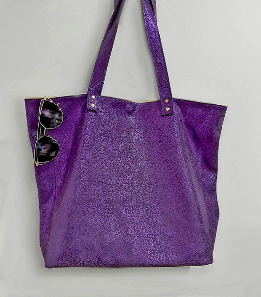 Purple tote bag with sunglasses on a light gray background. metallic small floral print on suede