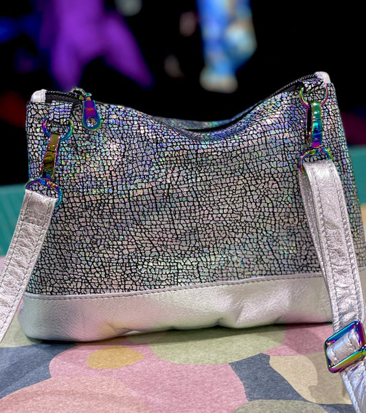 Silver textured handbag with silver metallic strap and on a paper surface