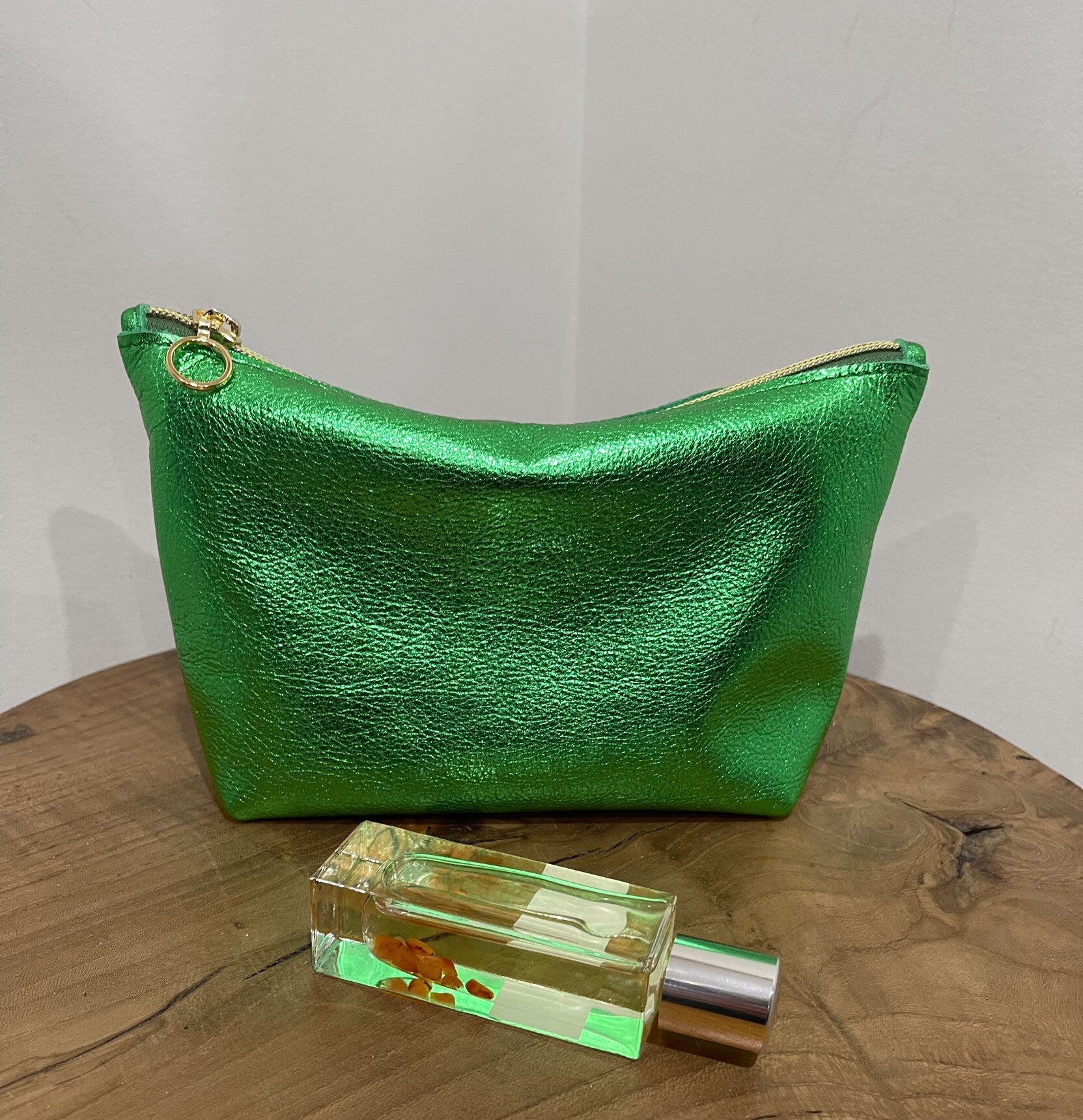 Medium size Green metallic makeup purse shown with a perfume bottle.