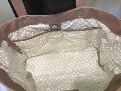 Close-up inside of pink tote bag with a patterned lining interior and magnet closure with key clasp.