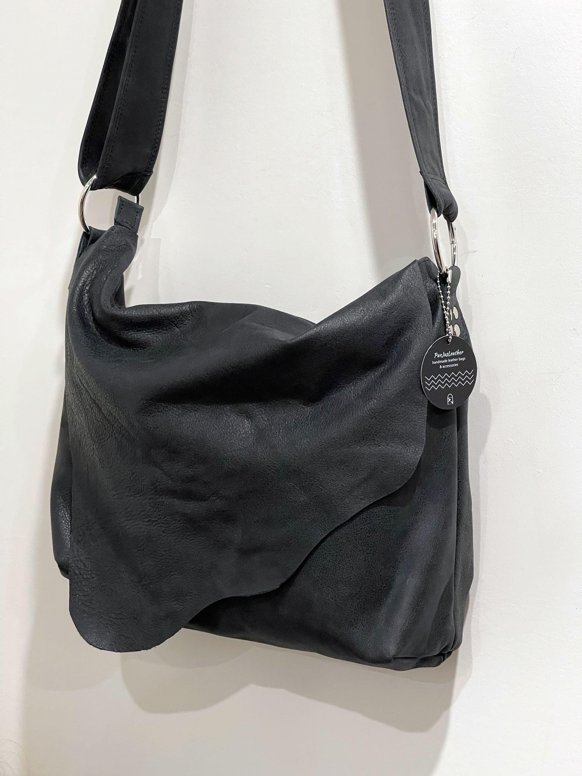 Matte Black bag with asymmetrical flap closure and large O ring strap attachment.