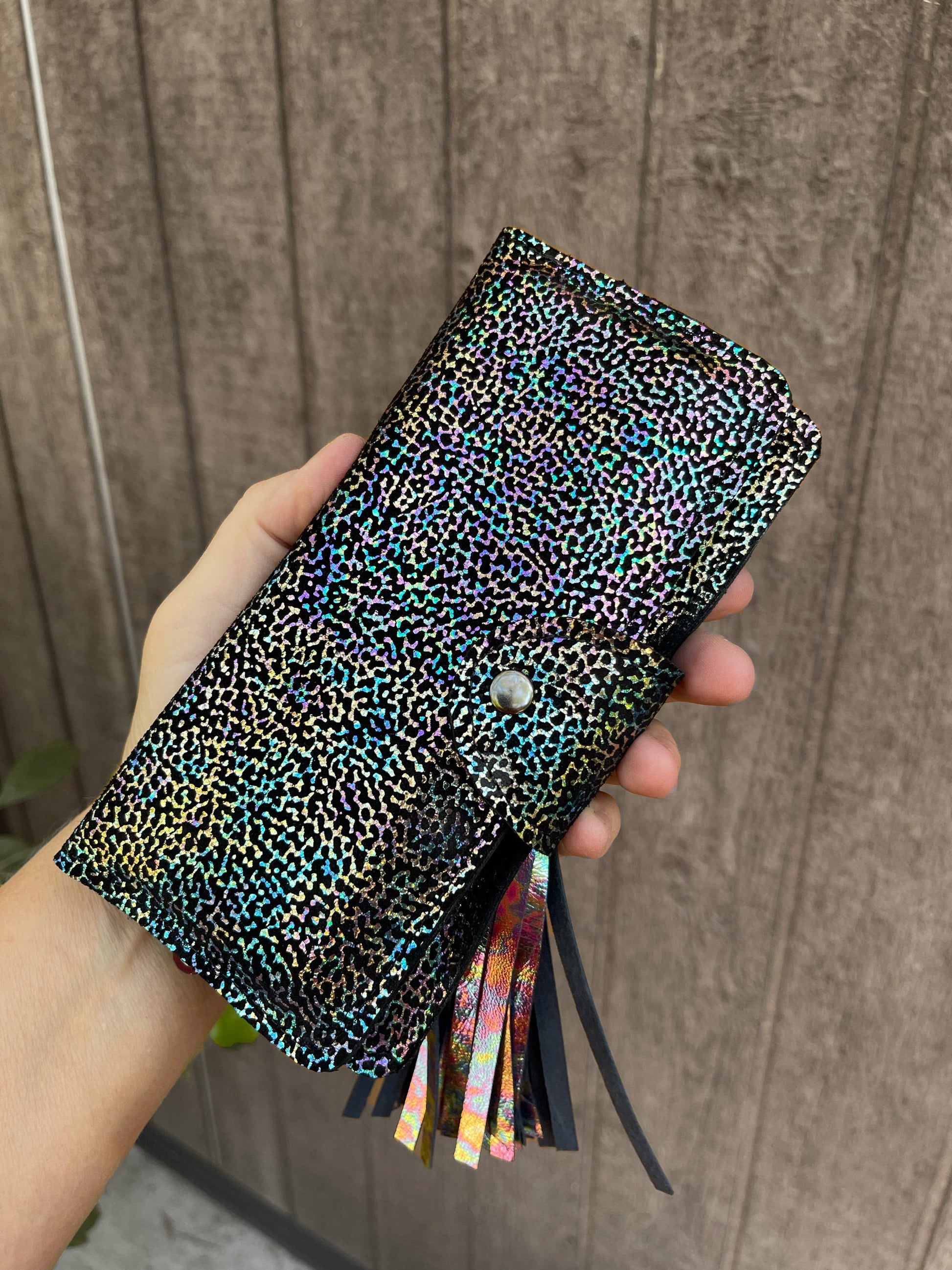 Hand holding a closed colorful patterned clutch purse wallet showing size