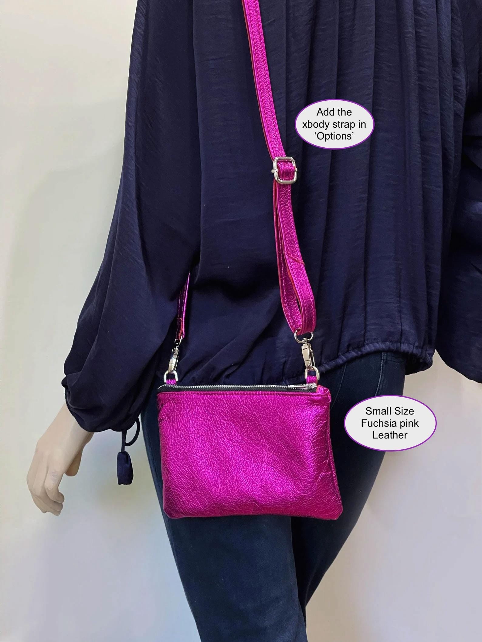 Person wearing a dark blue outfit with a fuchsia metallic pink leather handbag with detachable crossbody strap option and zipper closure silver hardware