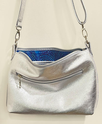 Silver handbag with a blue interior on a beige background