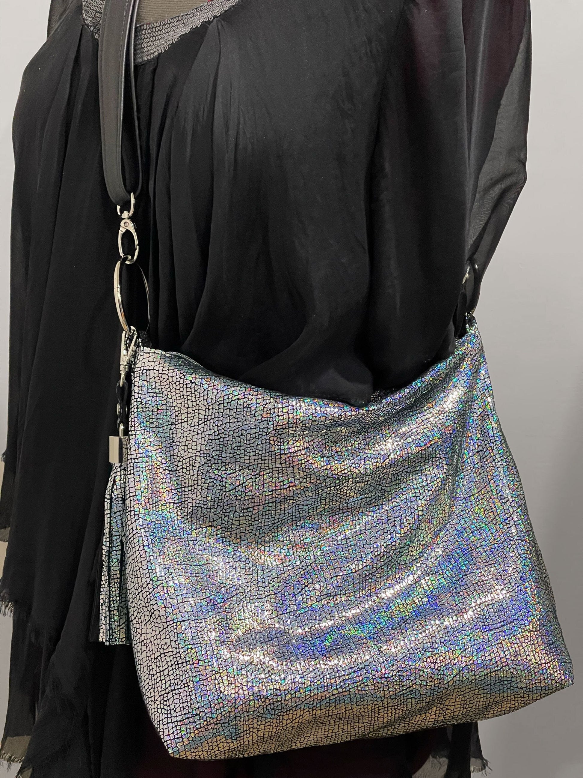 Silver glittery handbag on a model with detachable black strap o large rings
