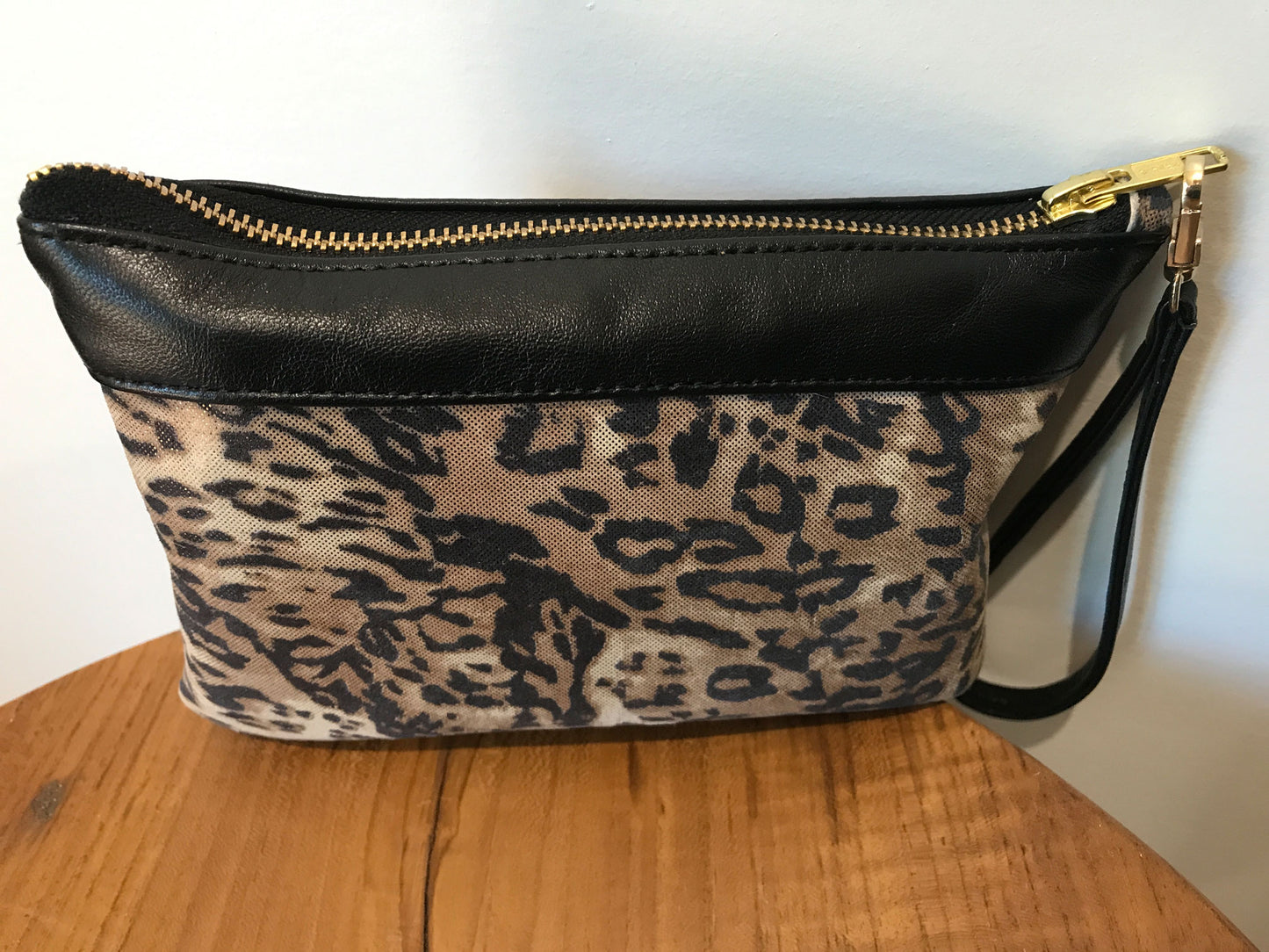 Leopard print clutch with black leather top section and brass hardware