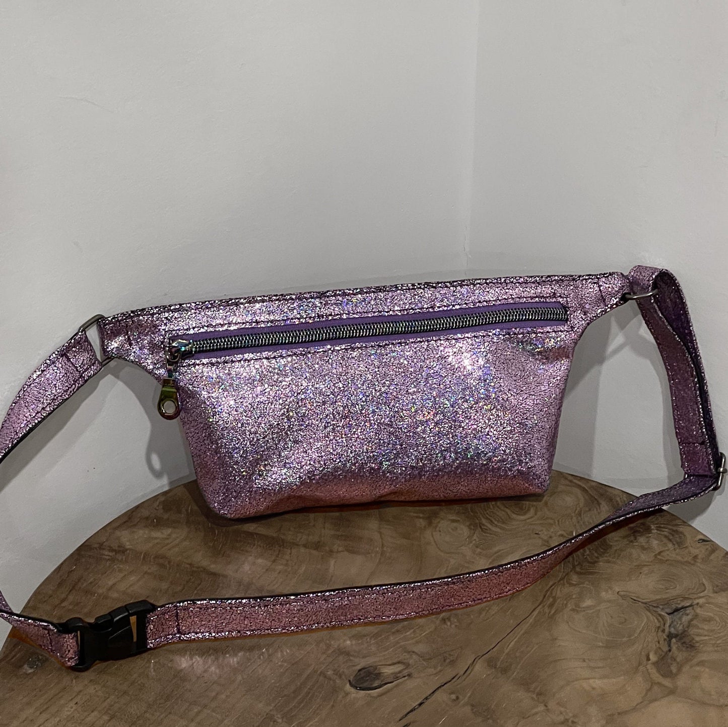 Glittery pink fanny pack on a wooden surface with a white background