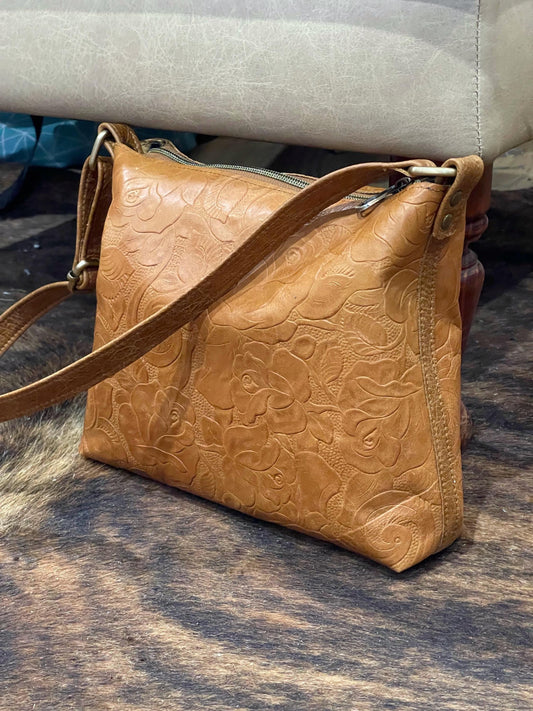 Brown leather handbag with embossed design on a textured surface