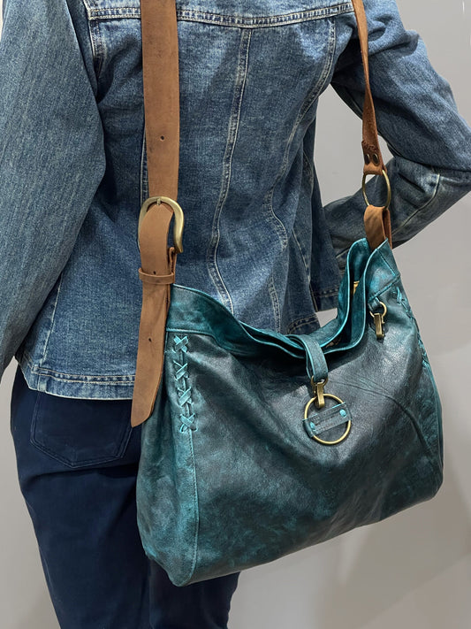 Vintage teal green boheme handbag with brown strap worn by a person wearing denim