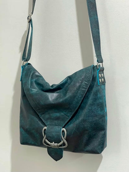 vintage Teal leather handbag with silver celtic buckle and flap closure on a white background