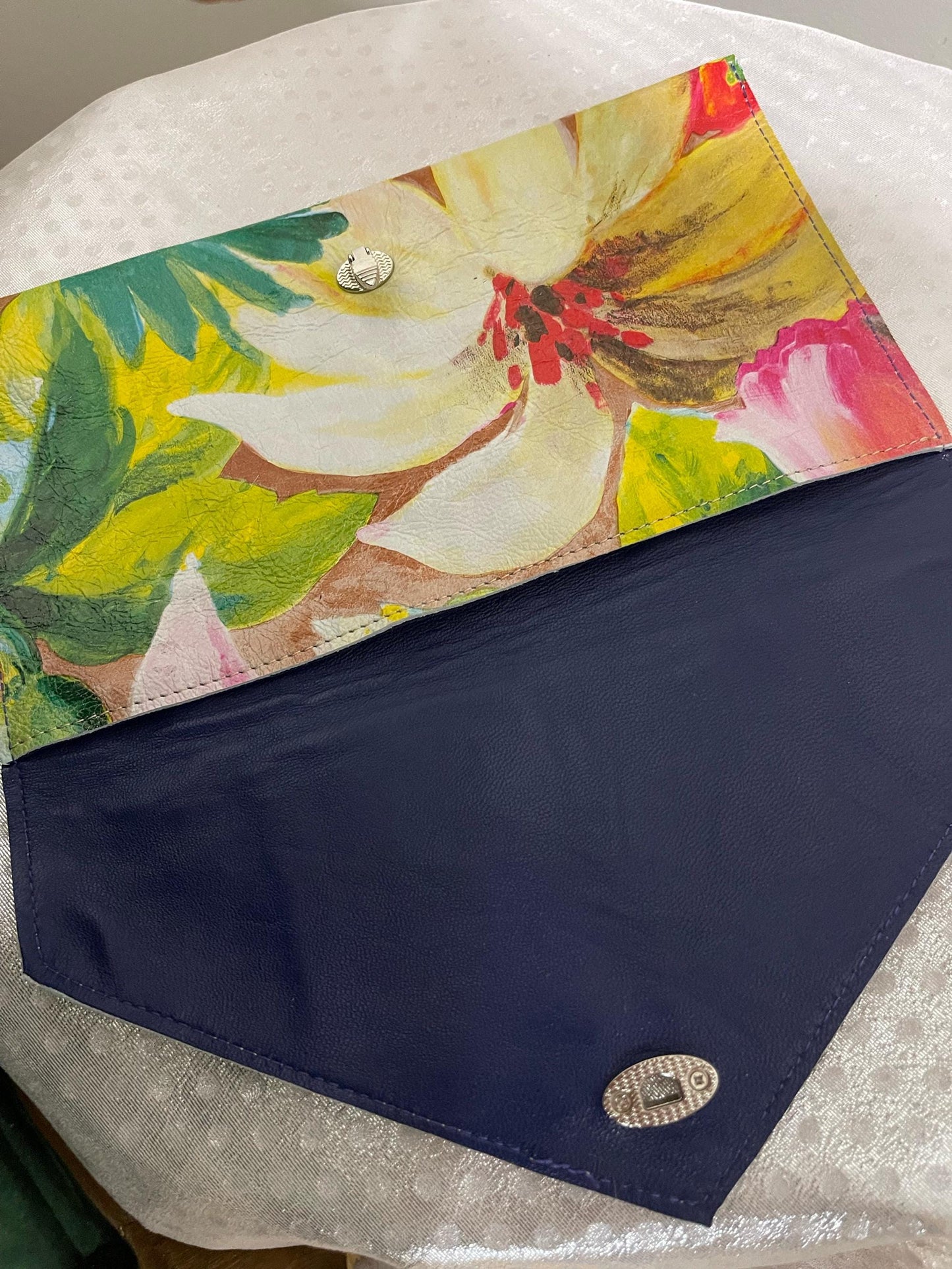 Floral-patterned clutch with a navy leather interior on a white surface