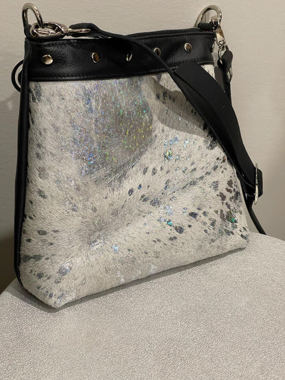 holo acid washed white cowhide bag and black accents on a neutral background