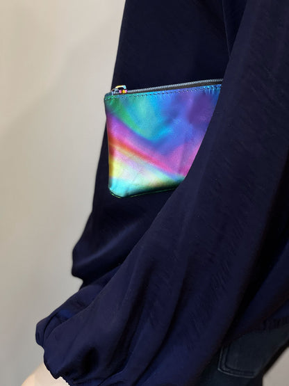 Navy blue silk shirt with a colorful, lava flow print zipper purse tucked under the models arm