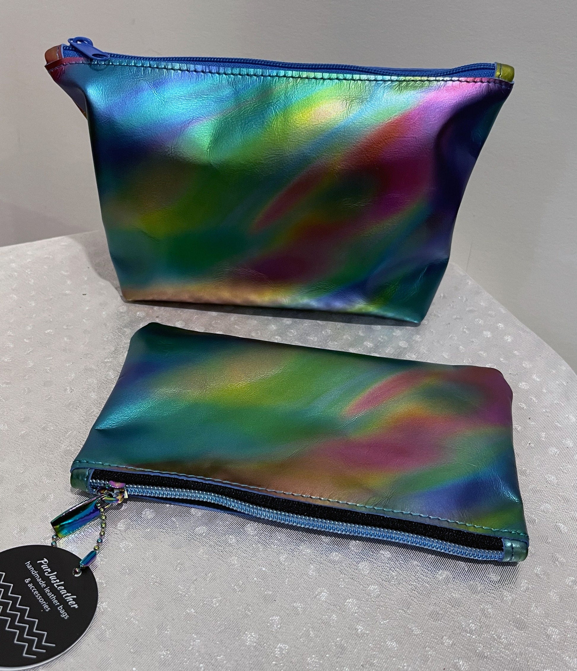 Two colorful pouches with a rainbow flowing pattern with easy glide zipper on a white surface.