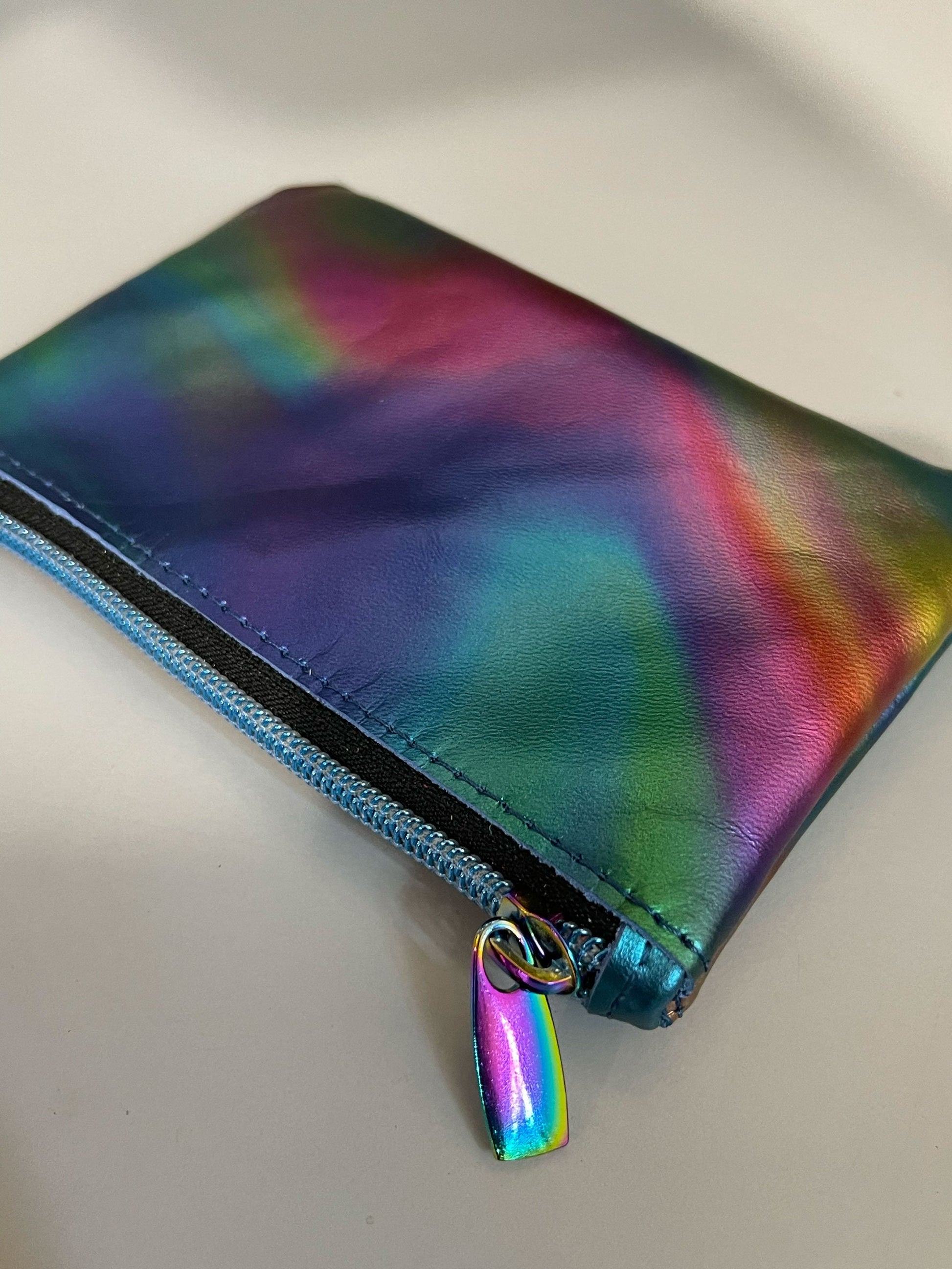 Multicolored zippered pouch with a rainbow zipper pull on a light gray background