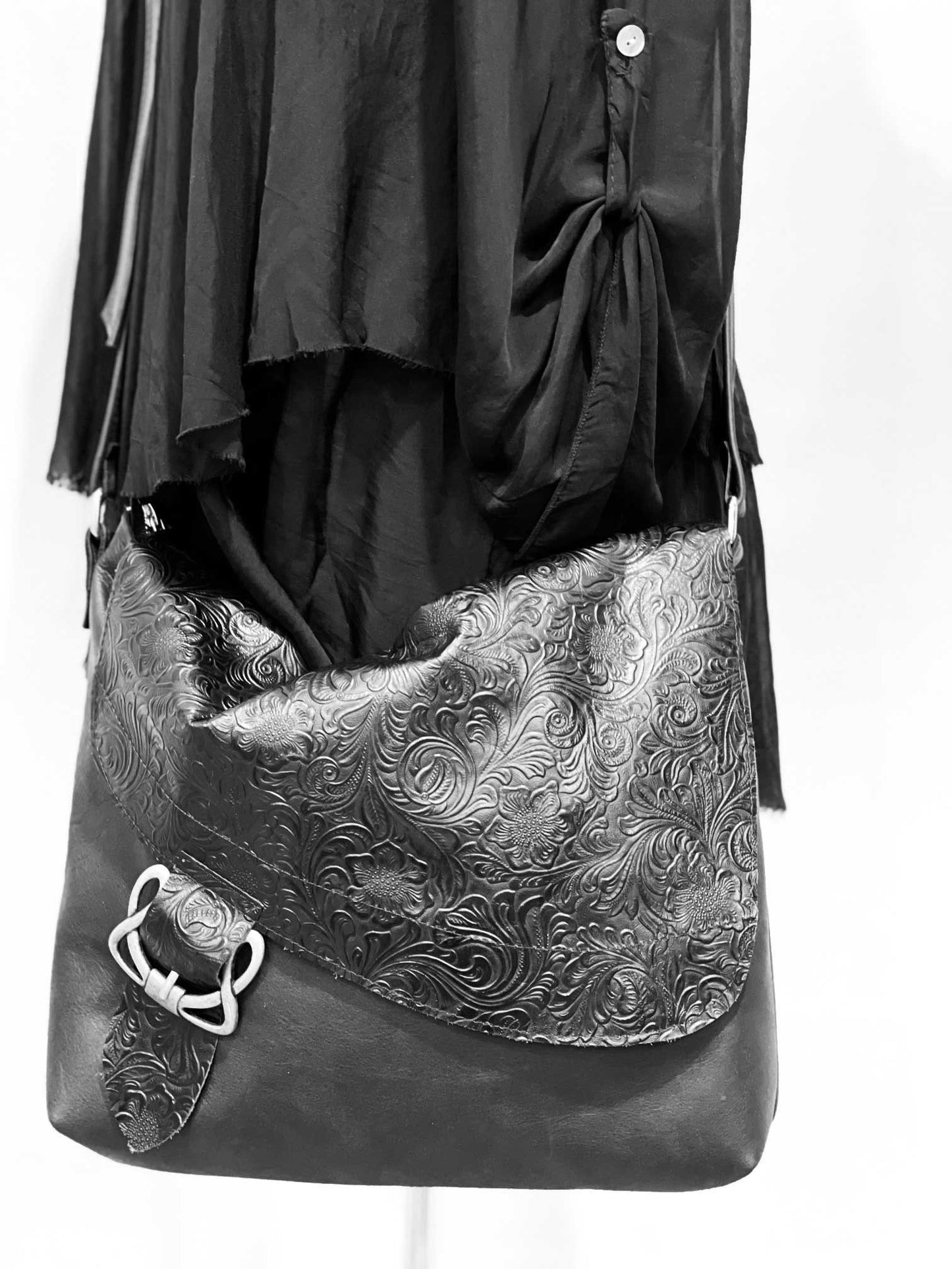 Black leather bag with intricate silver pattern on a white background