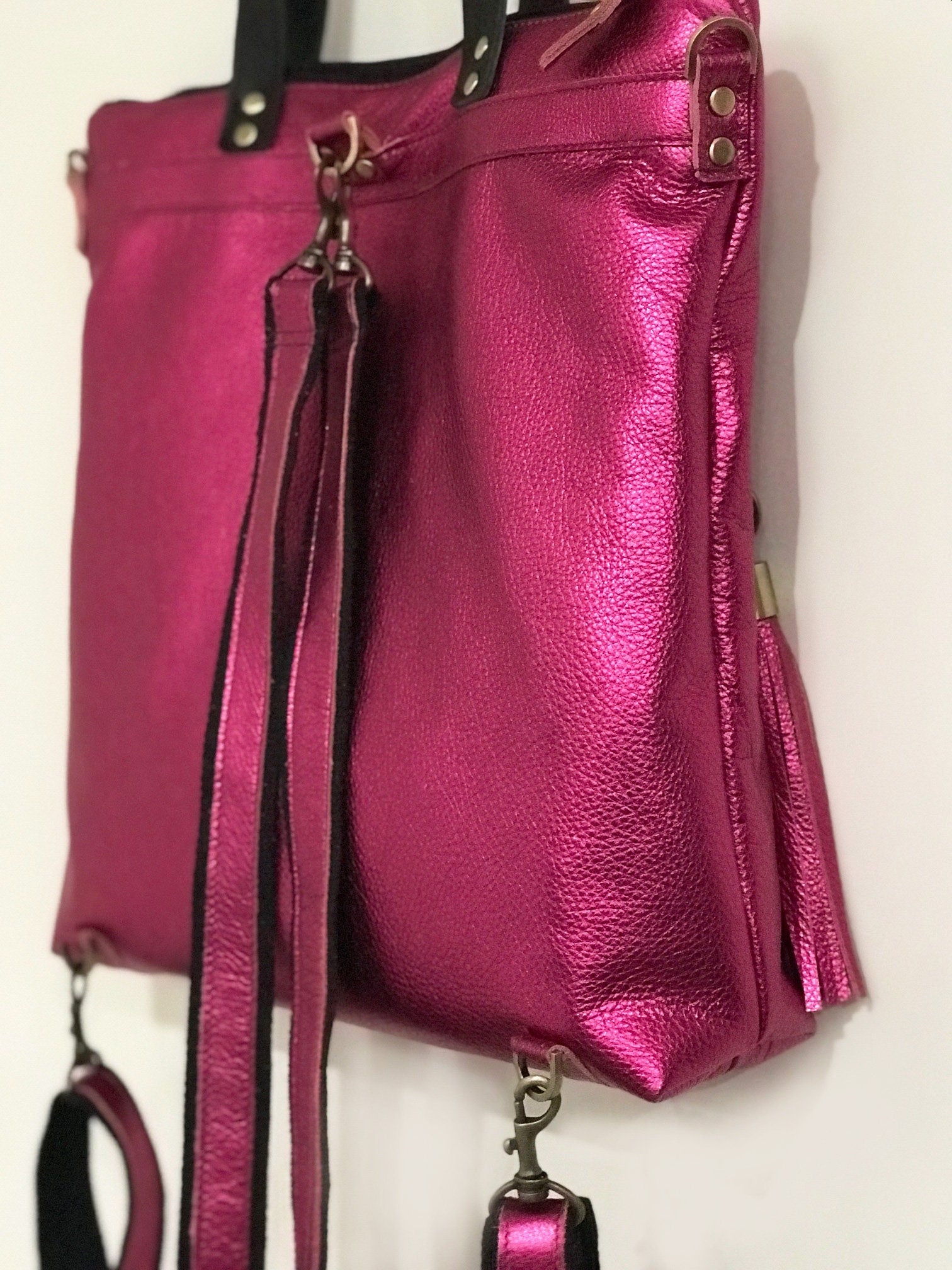 Pink leather backpack with a strap on a white background