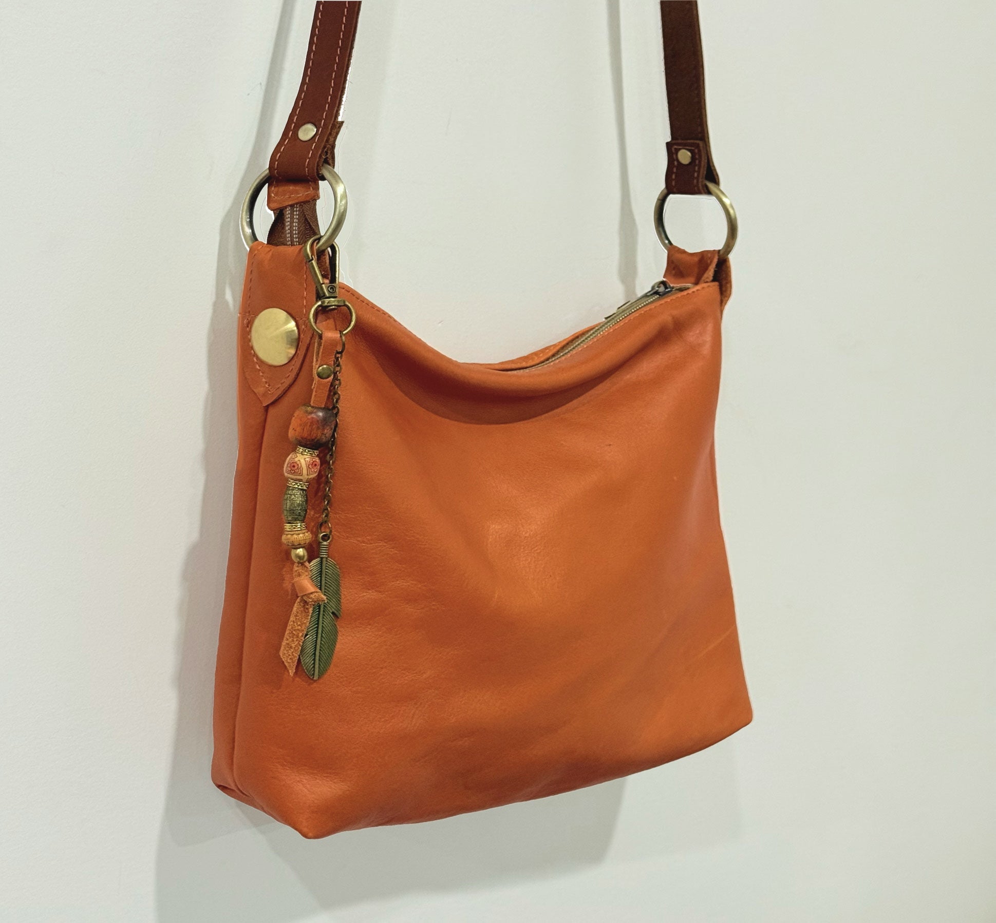 burnt orange tan bag with big brass stud feature and bead and metal bag charm