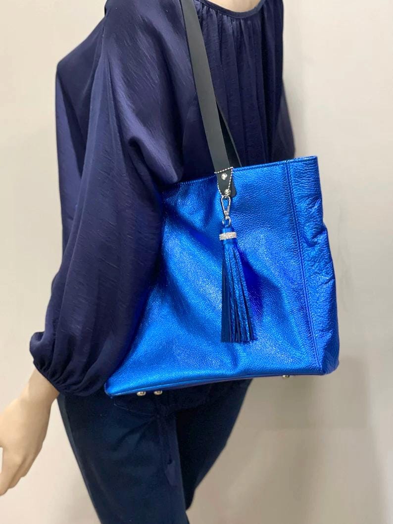 Blue handbag with a tassel on a mannequin against a beige background