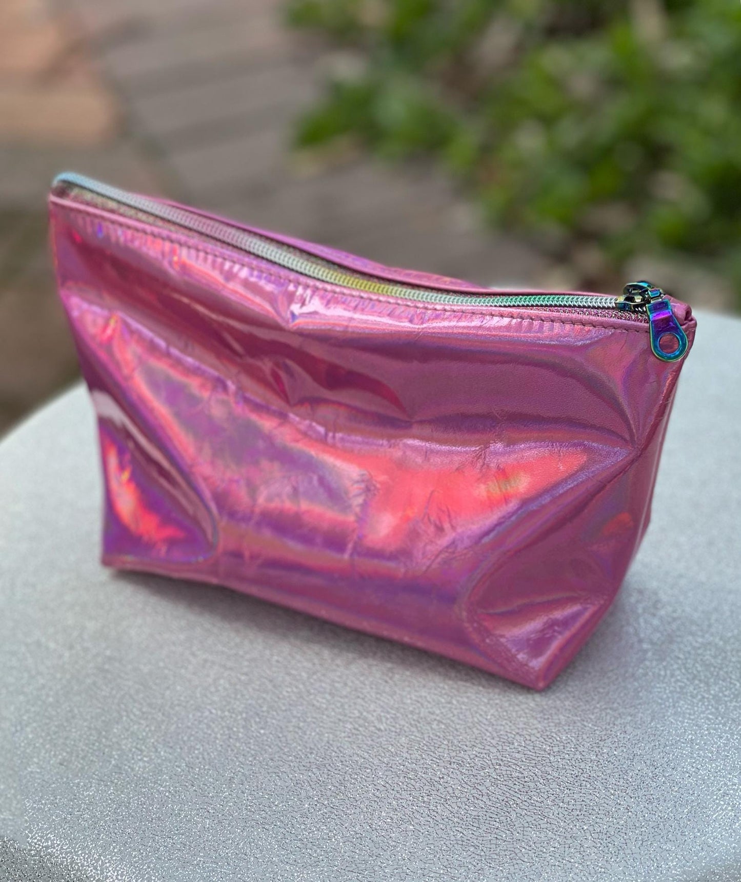 Holographic pink pouch outside with sun reflection and rainbow zipper closure