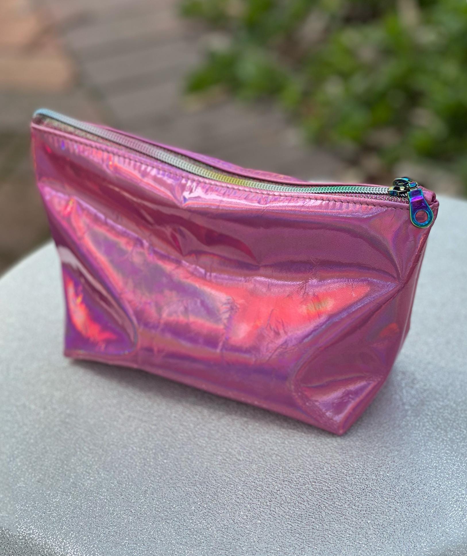 Holographic pink pouch outside with sun reflection and rainbow zipper closure
