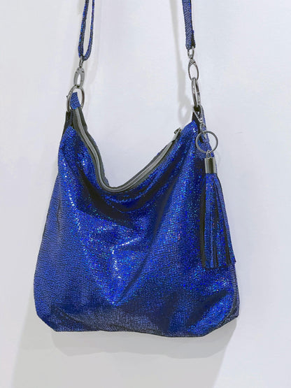 Cobalt Blue iridescent handbag with top zipper closure and tassel with a strap on a white background