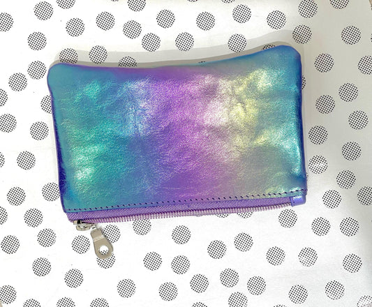 Iridescent coin purse on a white background with black polka dots