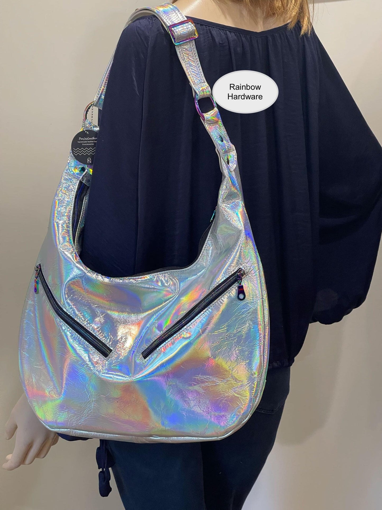 Holographic handbag worn by a person with a visible brand label on a plain background