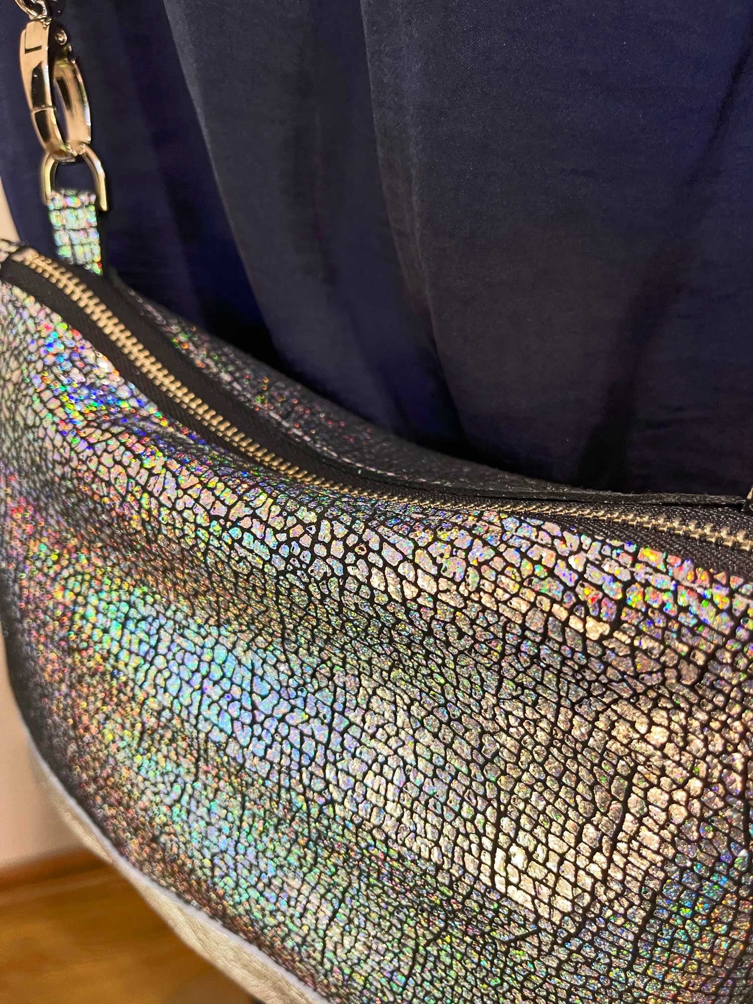 Holographic clutch bag with a silver metal zipper on a dark background