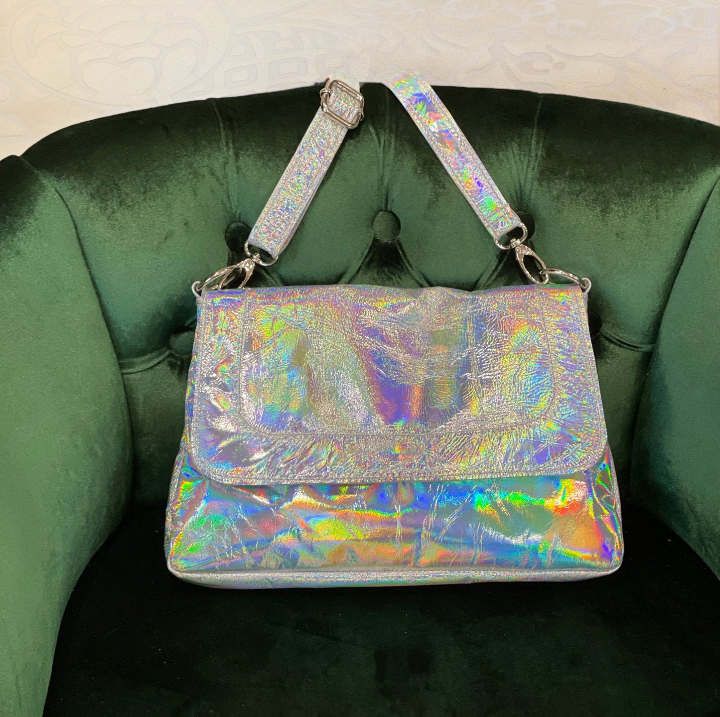 Holographic handbag with flap closure on a green velvet chair