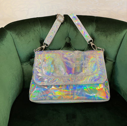 Holographic handbag with flap closure on a green velvet chair