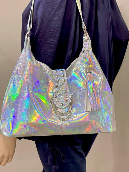 Holographic handbag with embellishments held by a person wearing a dark outfit.