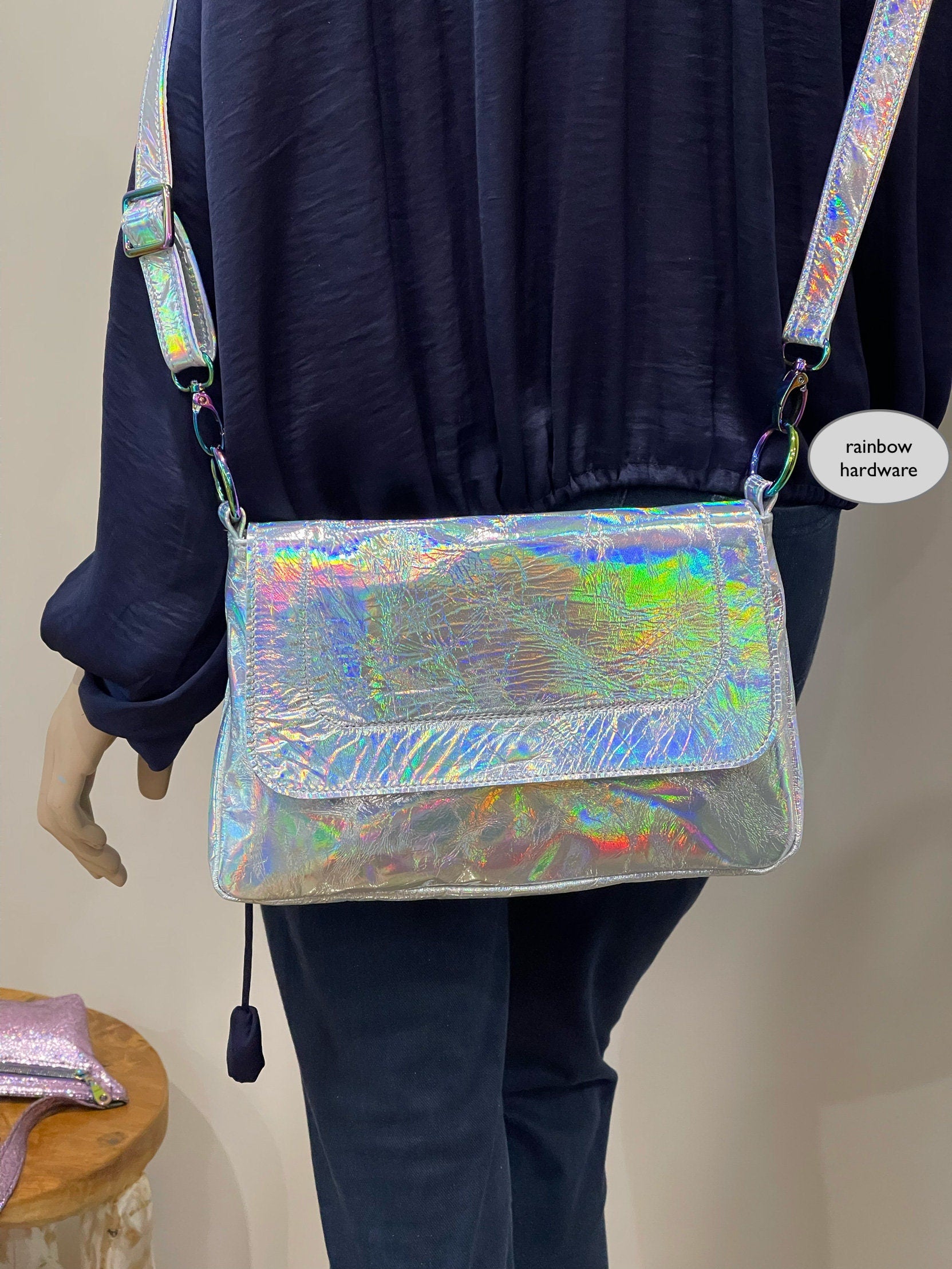 Person wearing a reflective silver crossbody bag with colorful hardware.