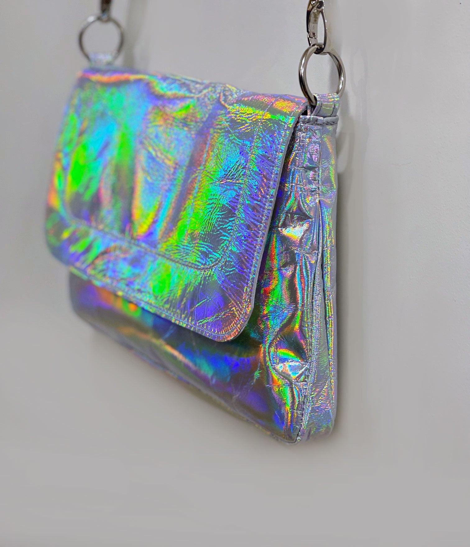Holographic clutch bag with flap side angle showing the depth of the bag and strap attachment on O rings.