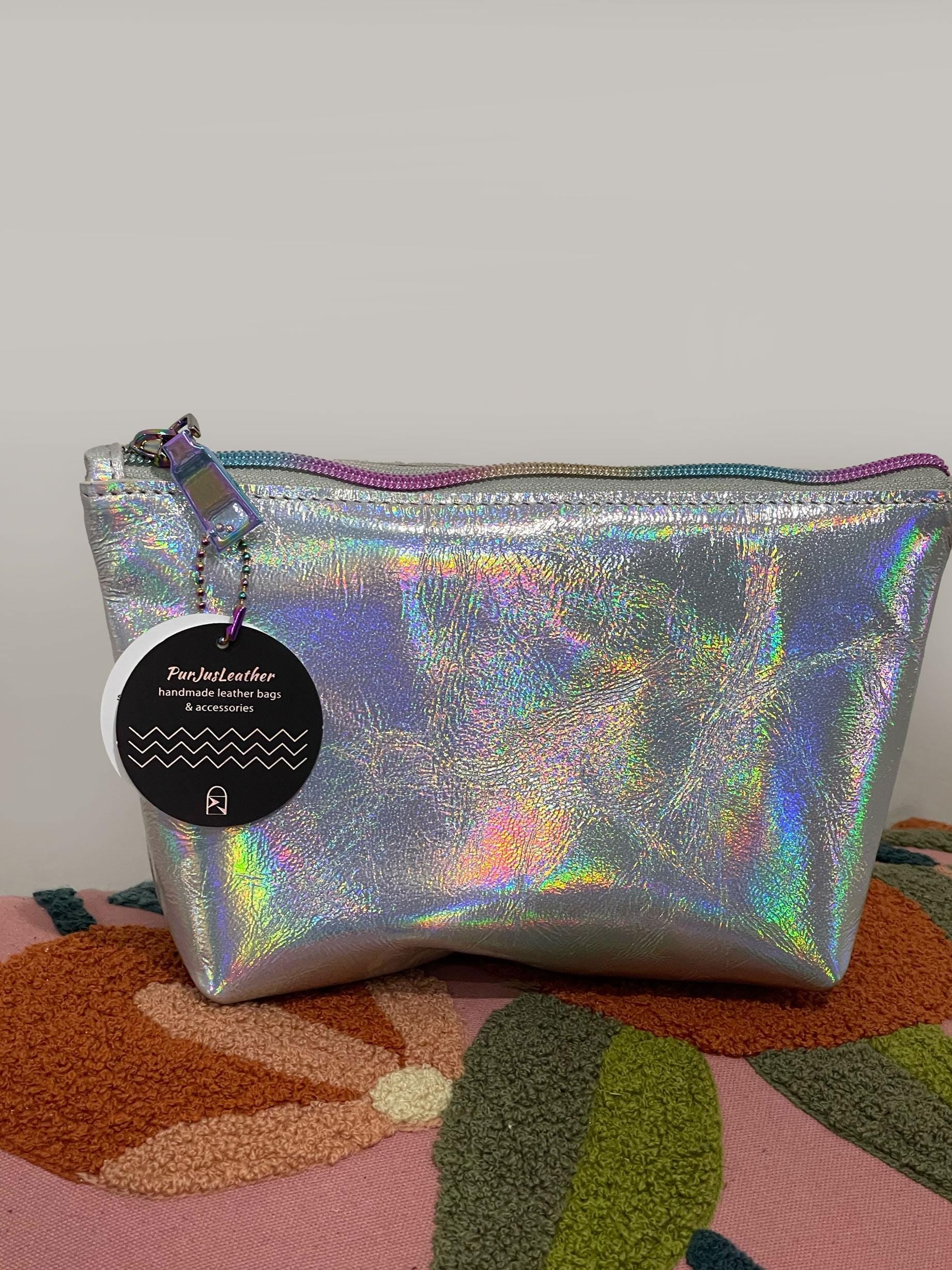 Holographic pouch with rainbow zipper on grey on a textured surface