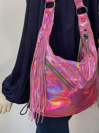 Holographic pink handbag with fringe details and front zipper pockets on a plain background
