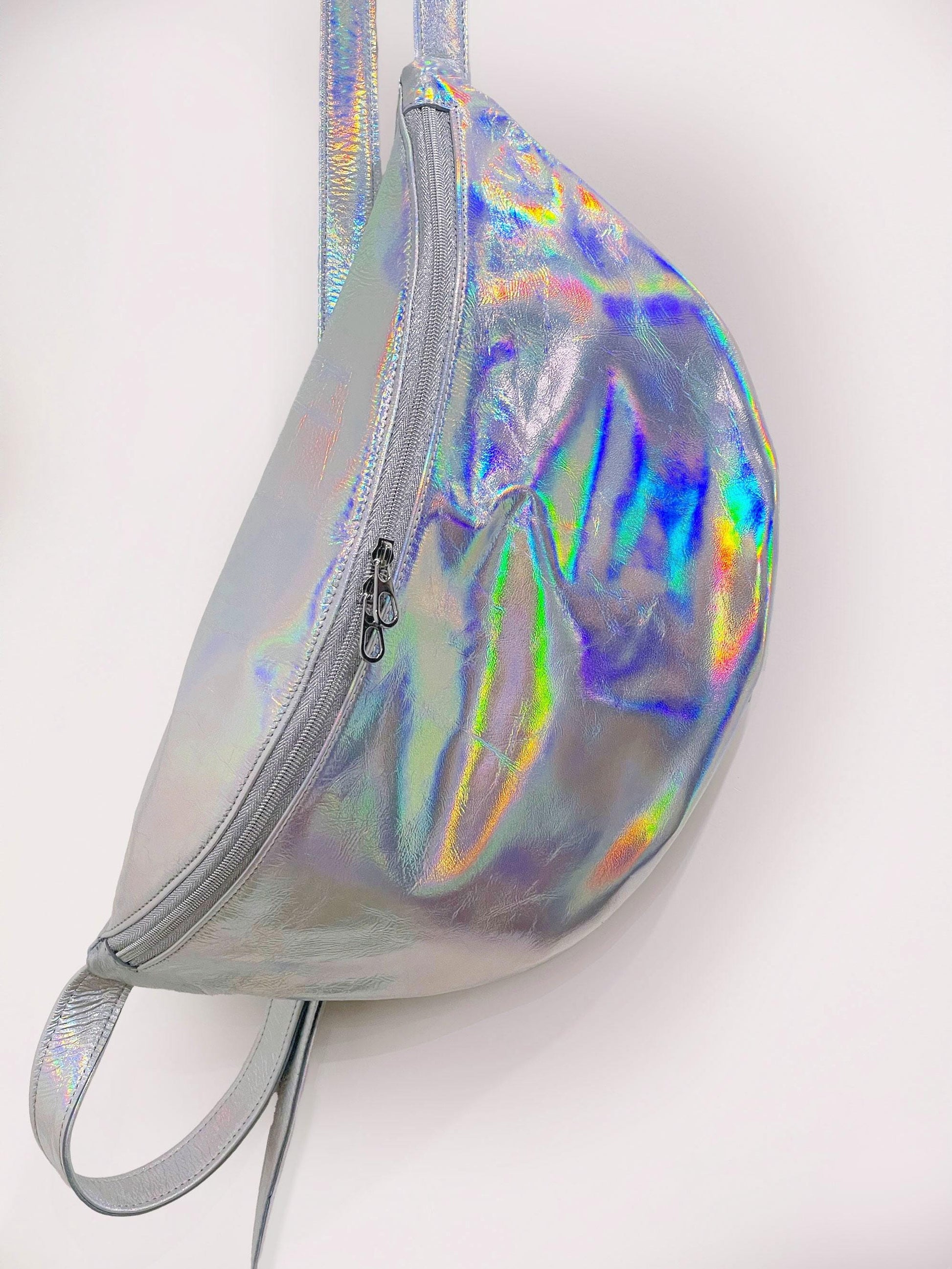 XLarge Holographic fanny pack with 2 zipper pulls showing blues and green yellow reflective colour on a white background.