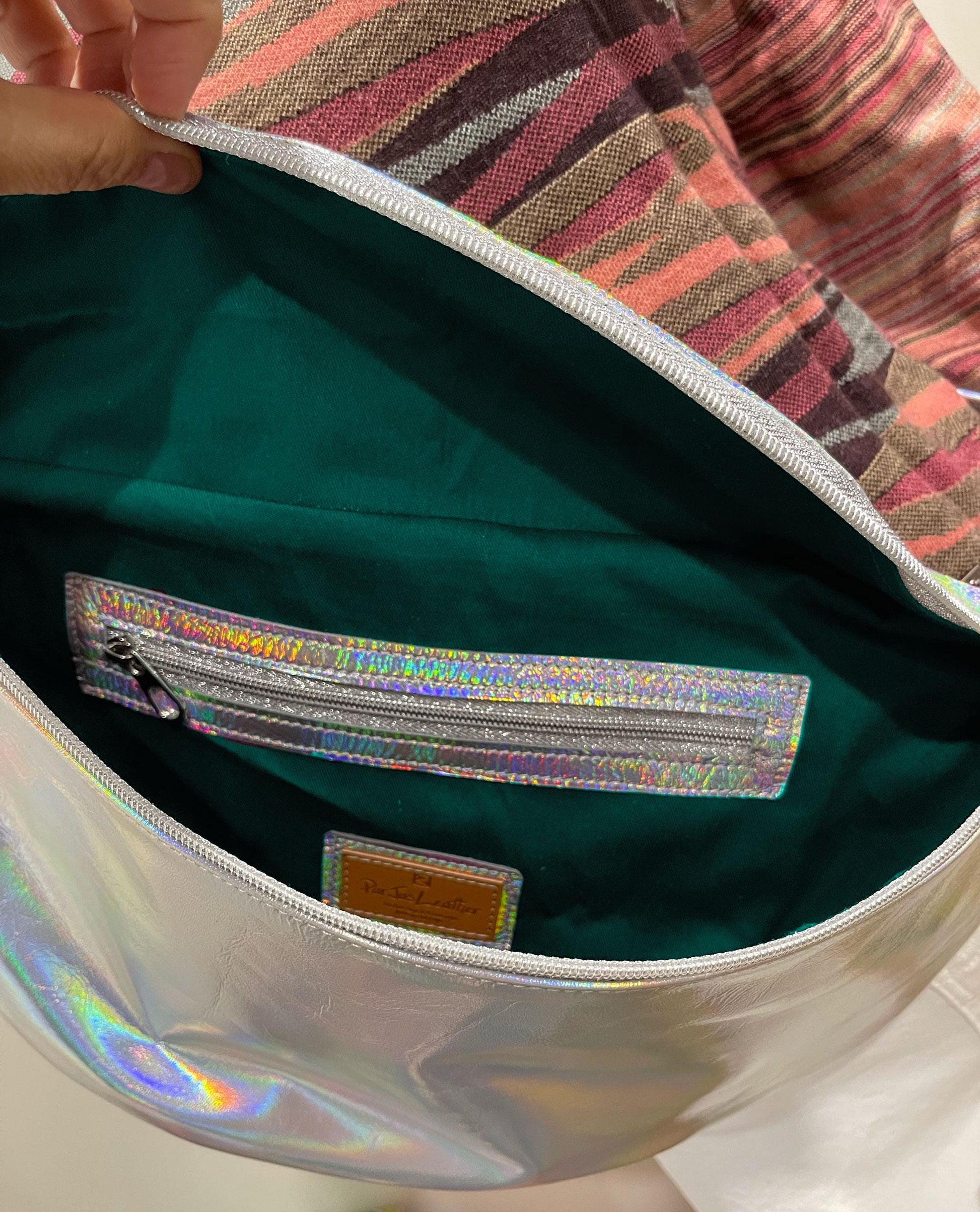 Close-up of holographic sling bag lining in teal with inside zipper pocket and easy slide zipper closure