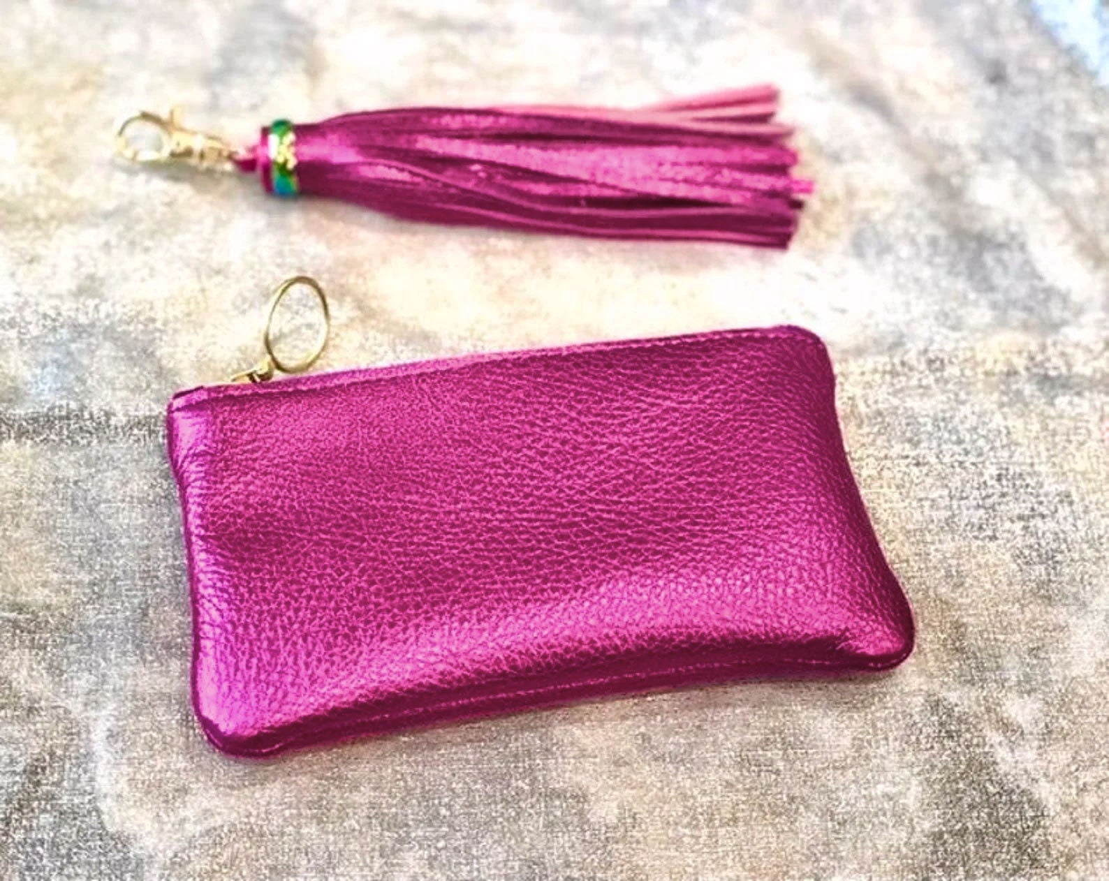 Pink leather pouch with tassel on a textured surface