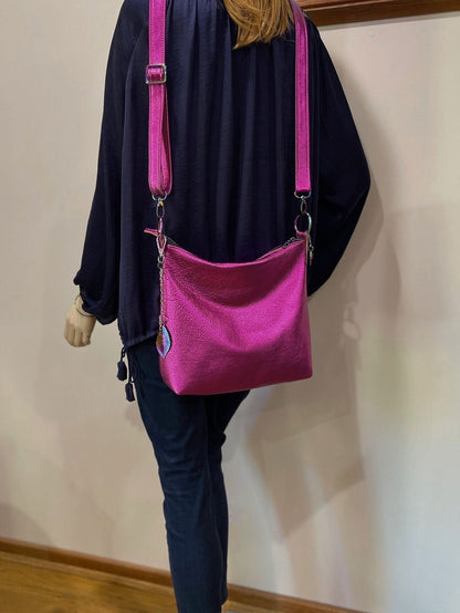 Person wearing a navy silk blouse and jeans with a bright pink shoulder bag against a plain wall.