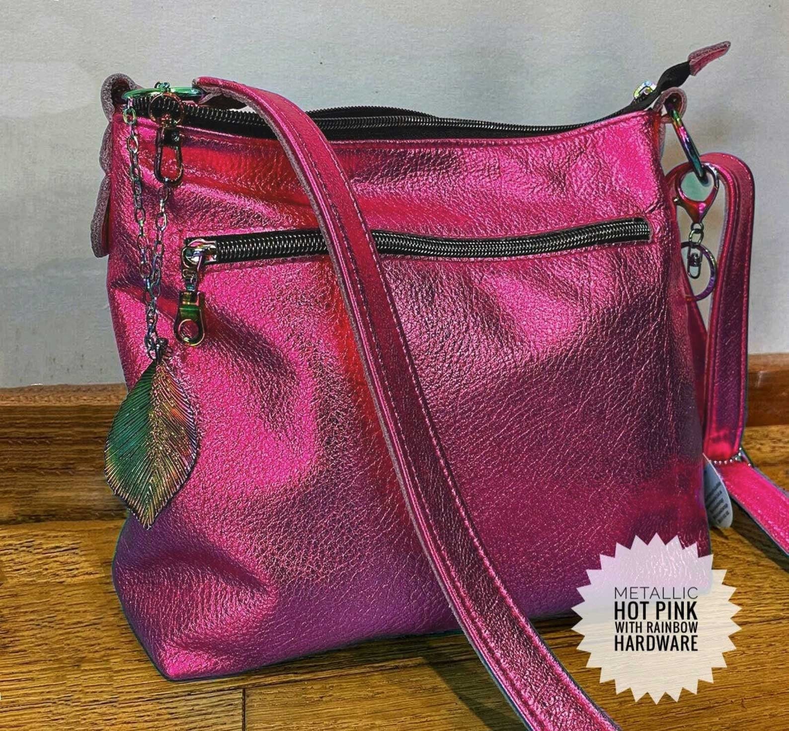 Pink metallic handbag with rainbow hardware on a wooden surface