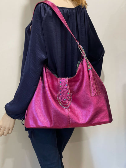 Person wearing a bright pink handbag with decorative rainbow chain and rivet elements on a plain background