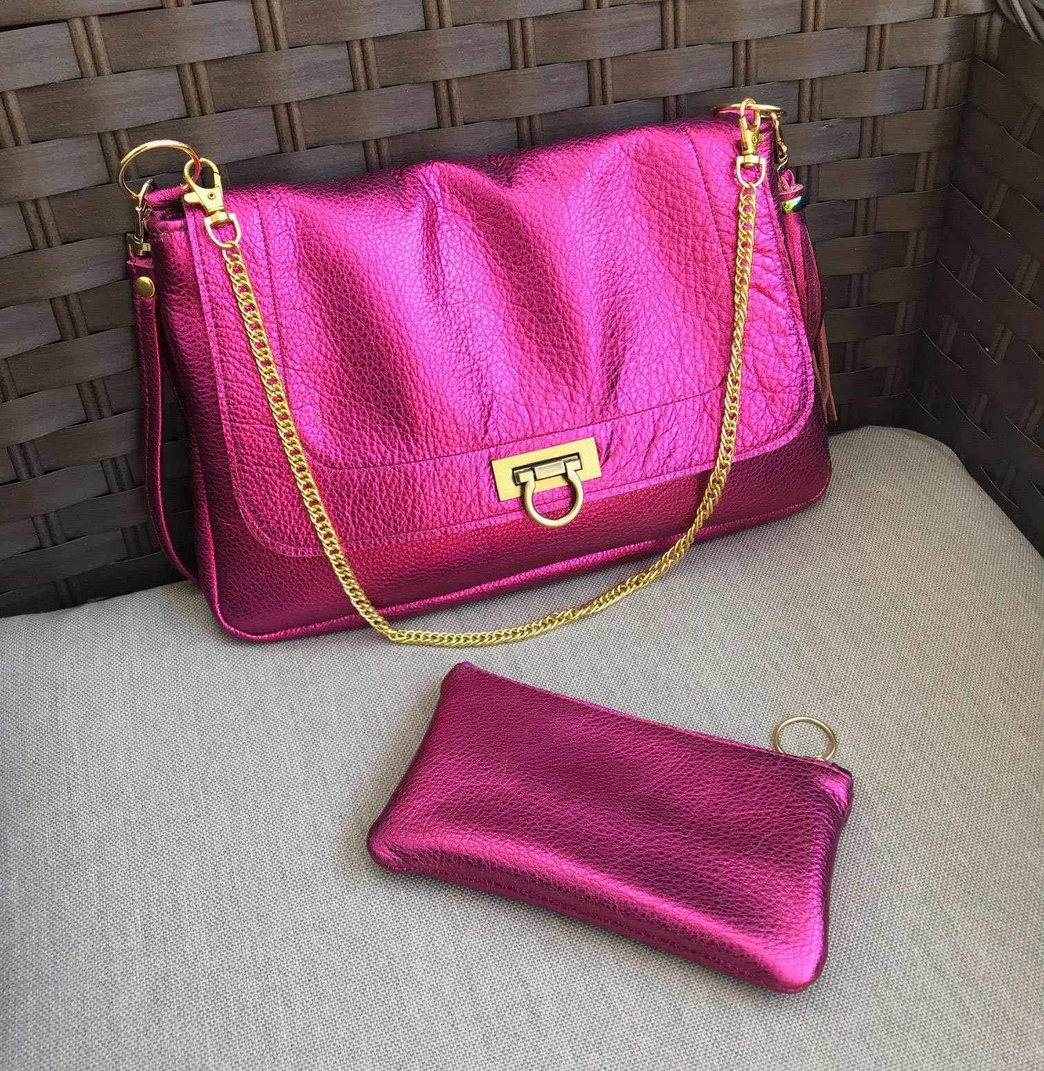 Pink handbag with gold chain and matching wallet on a textured surface