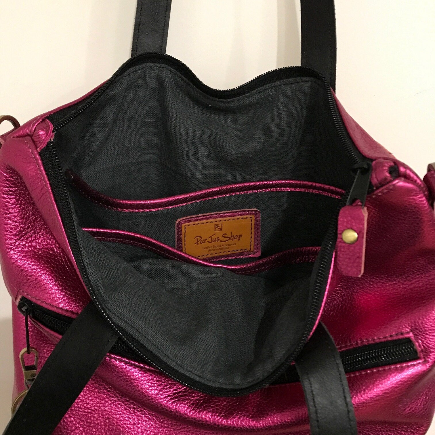 Close-up of a pink leather handbag with visible black lining, easy access inner bag showing slip pockets.