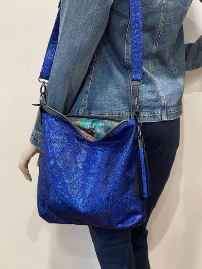 Blue glittery handbag worn by a mannequin against a neutral background