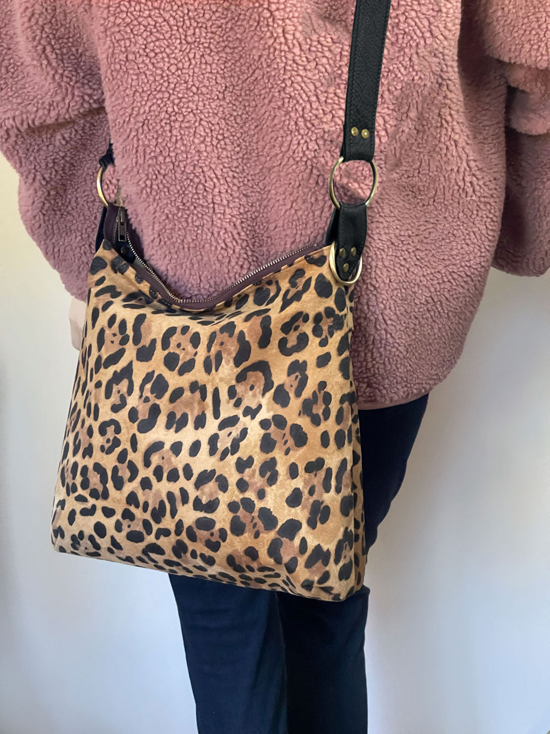 Leopard print handbag held by a person wearing a pink fleece jacket.