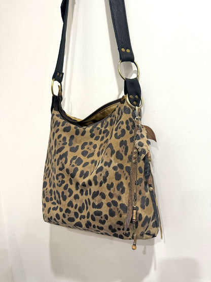 Leopard print handbag with a black strap on a white background