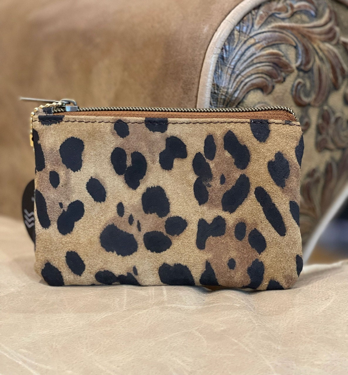 Leopard print pouch on a textured surface with a blurred background