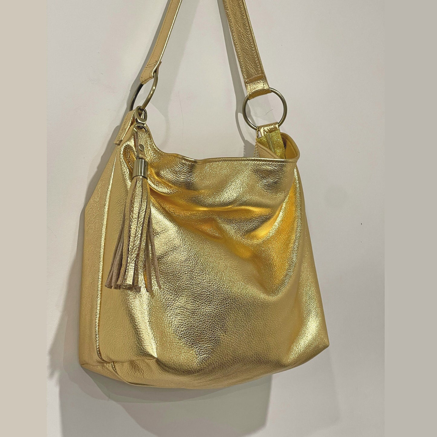 Gold handbag with a tassel on a light gray background