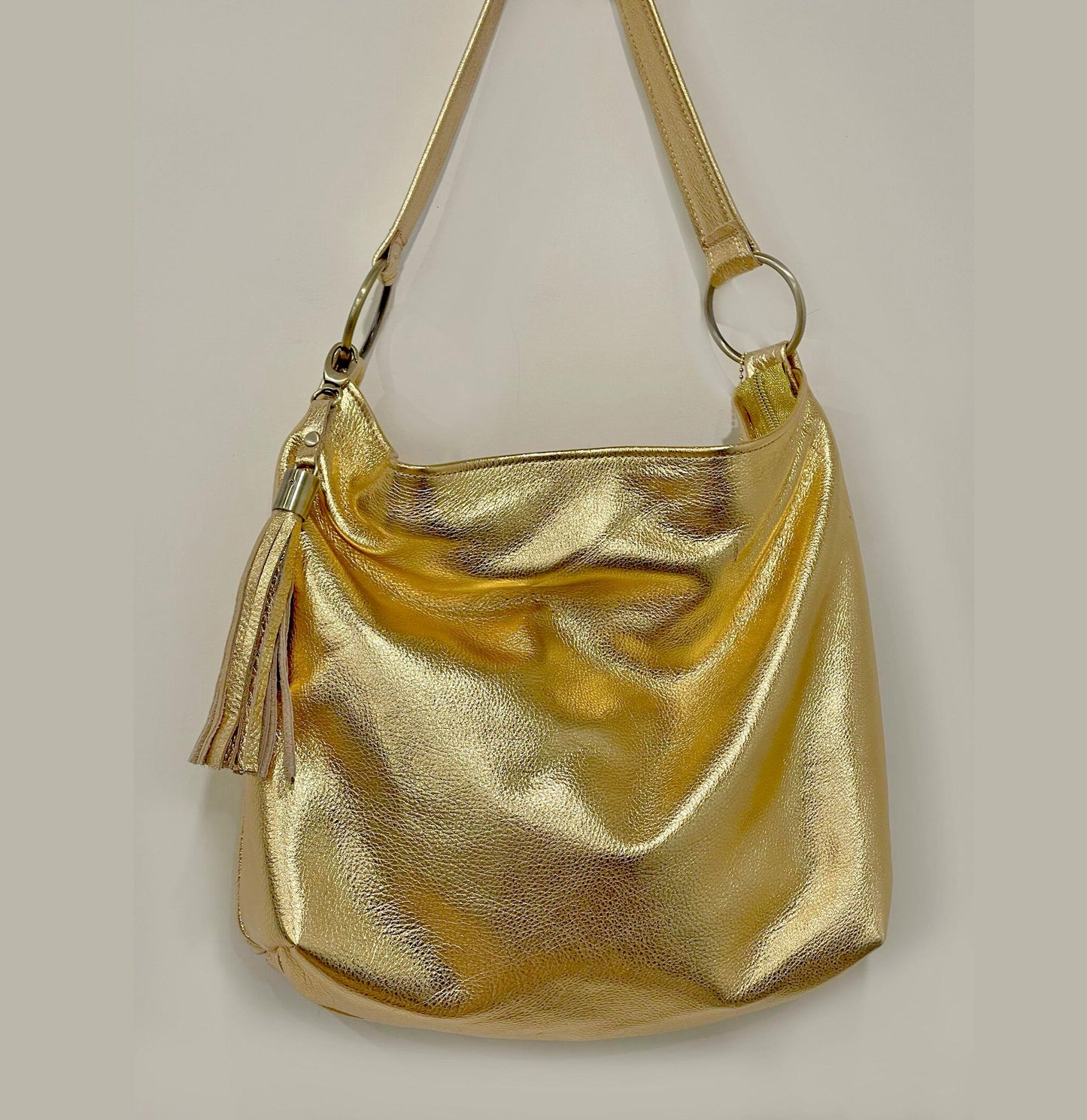 Gold metallic handbag scrunched to show how soft and pliable the leather is. Large O rings hold strap